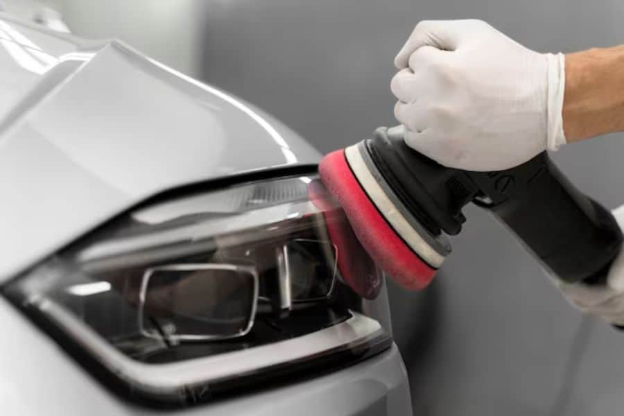 A person is polishing the headlight of a car.