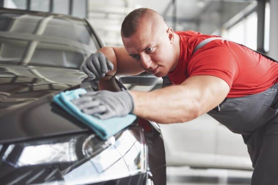 A man cleaning a car in a showroom.