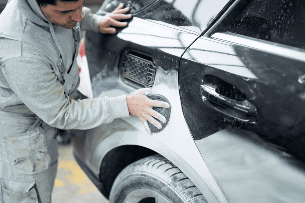 A man is painting a car in a garage.