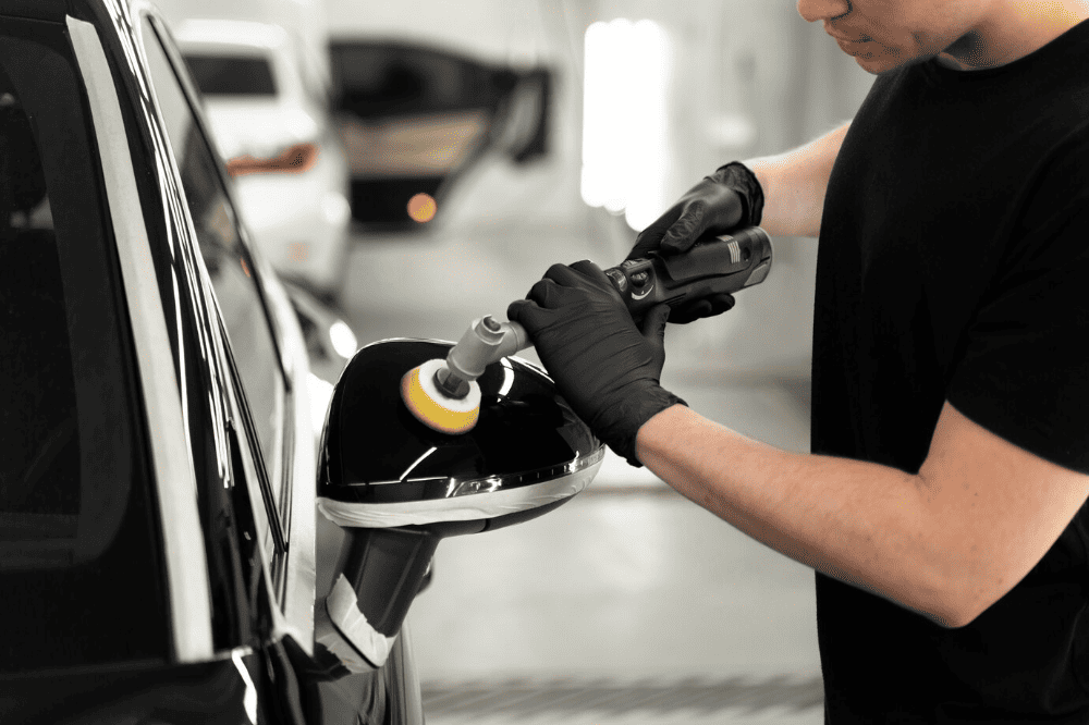 A man is polishing the door of a car.