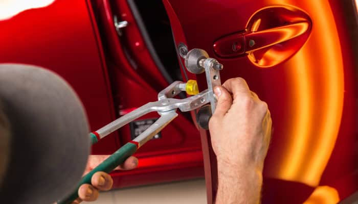 Dent repair being performed on a red car door at GemState PDR.